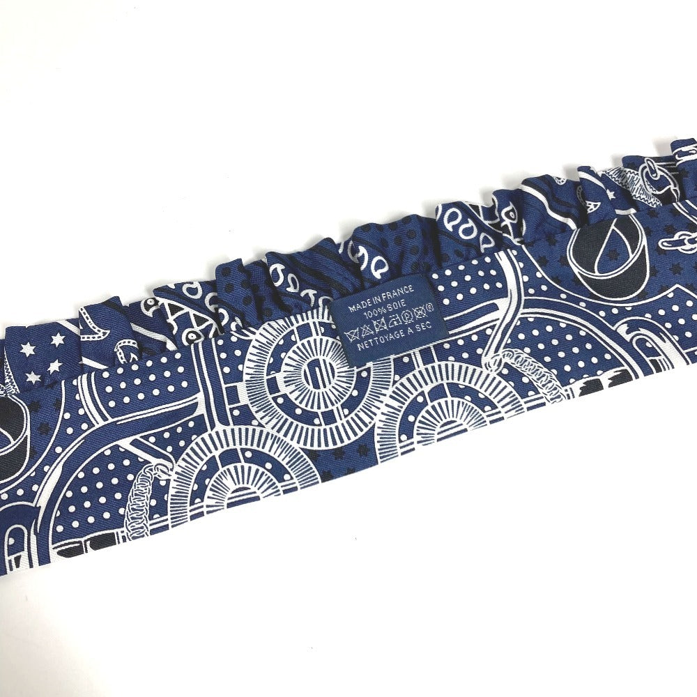 HERMES Apron d'Or, a silk scarf with a ruffled twilly lining, available in Marine Foncé, black, white, and blue.