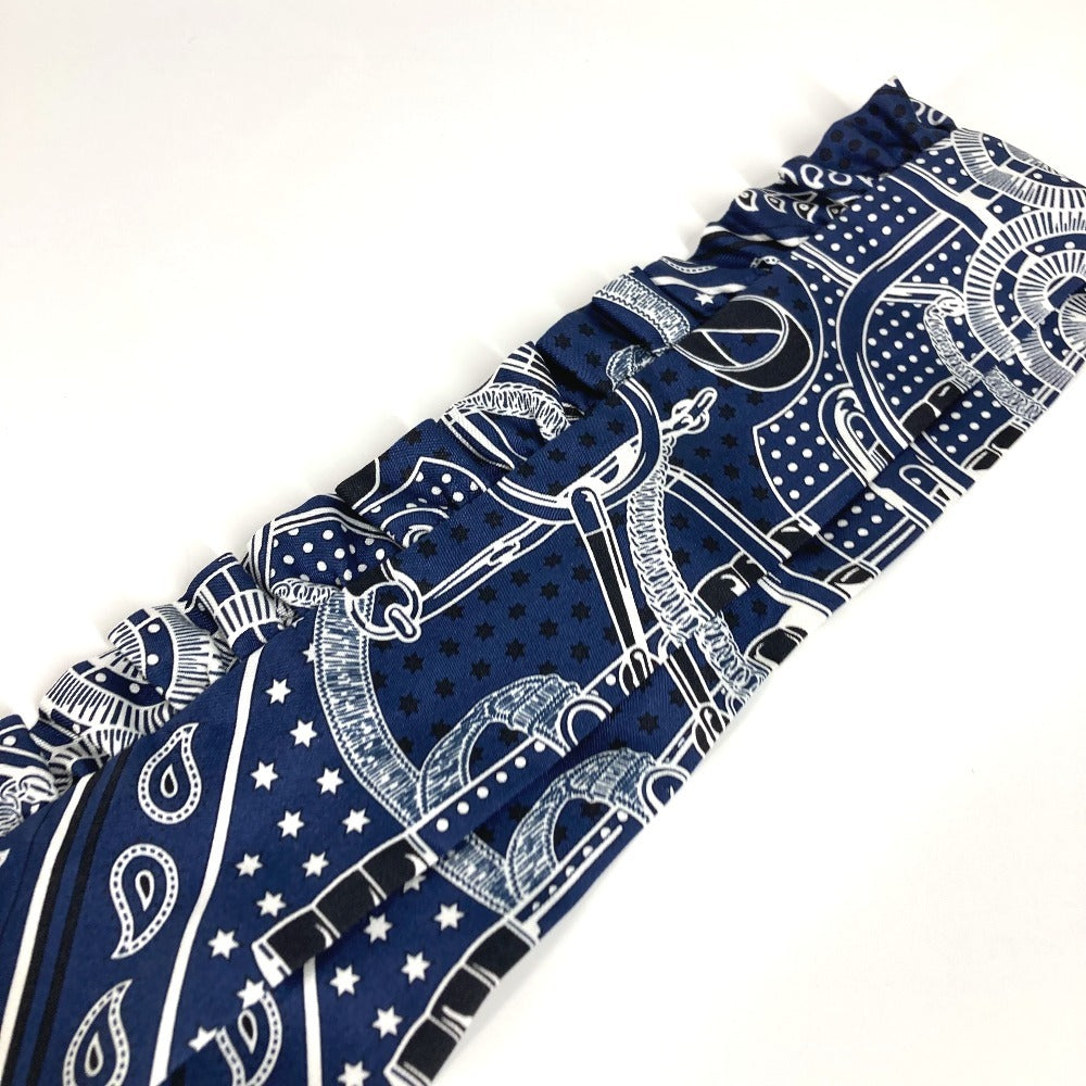 HERMES Apron d'Or, a silk scarf with a ruffled twilly lining, available in Marine Foncé, black, white, and blue.